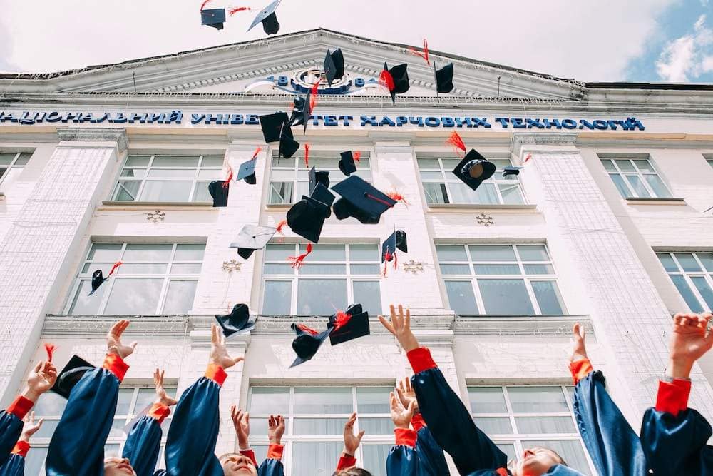 graduation caps thrown in front of a school