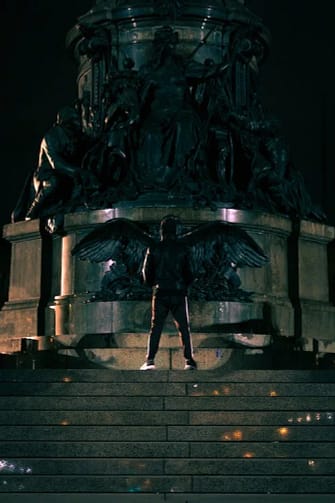 demon with wings standing in front of a statue