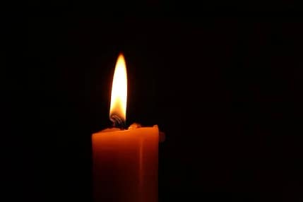 a candle burning with a black backdrop