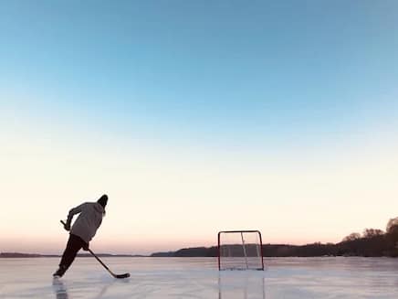 guy playing hockey with a net and a sunset