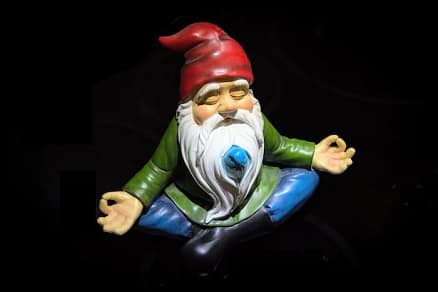 gnome doing yoga zen pose with black backdrop