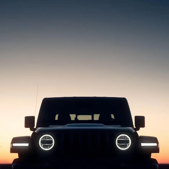 jeep in a sunset with sillouhette and lights on