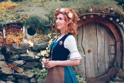 Female hobbit in front of a hobbit house