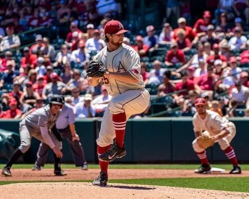 Baseball pitcher mid windup on baseball field with gray uniform