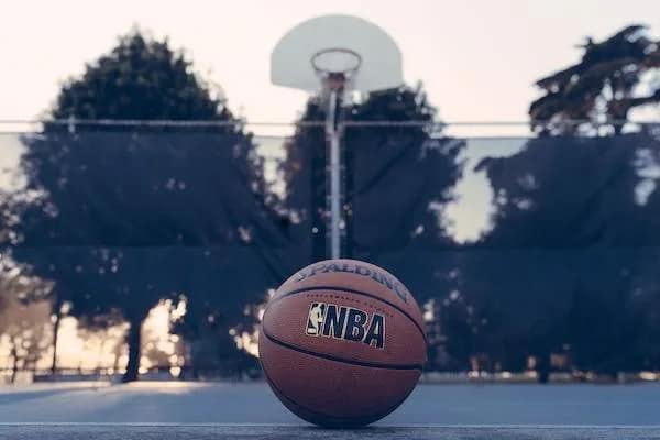 basketball with nba logo in front of basketball hoop