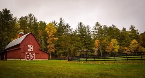 red barn with beautiful forest behind it