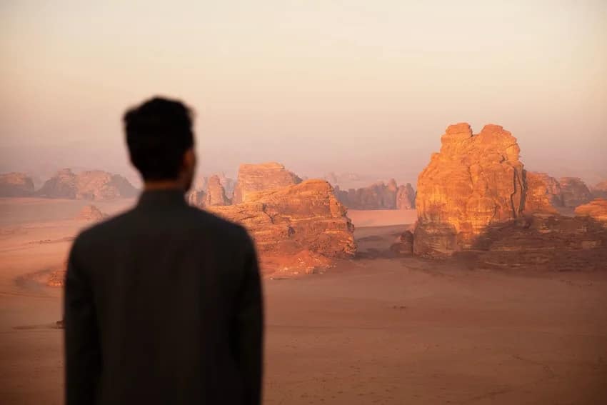 travel photo of guy standing in front of a desert with orange rock formations